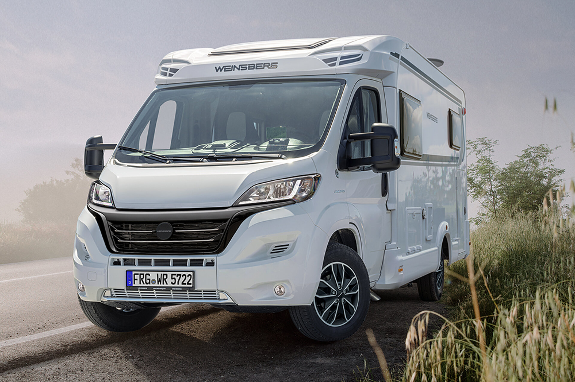 Un camping-car blanc sur une route dans le brouillard.