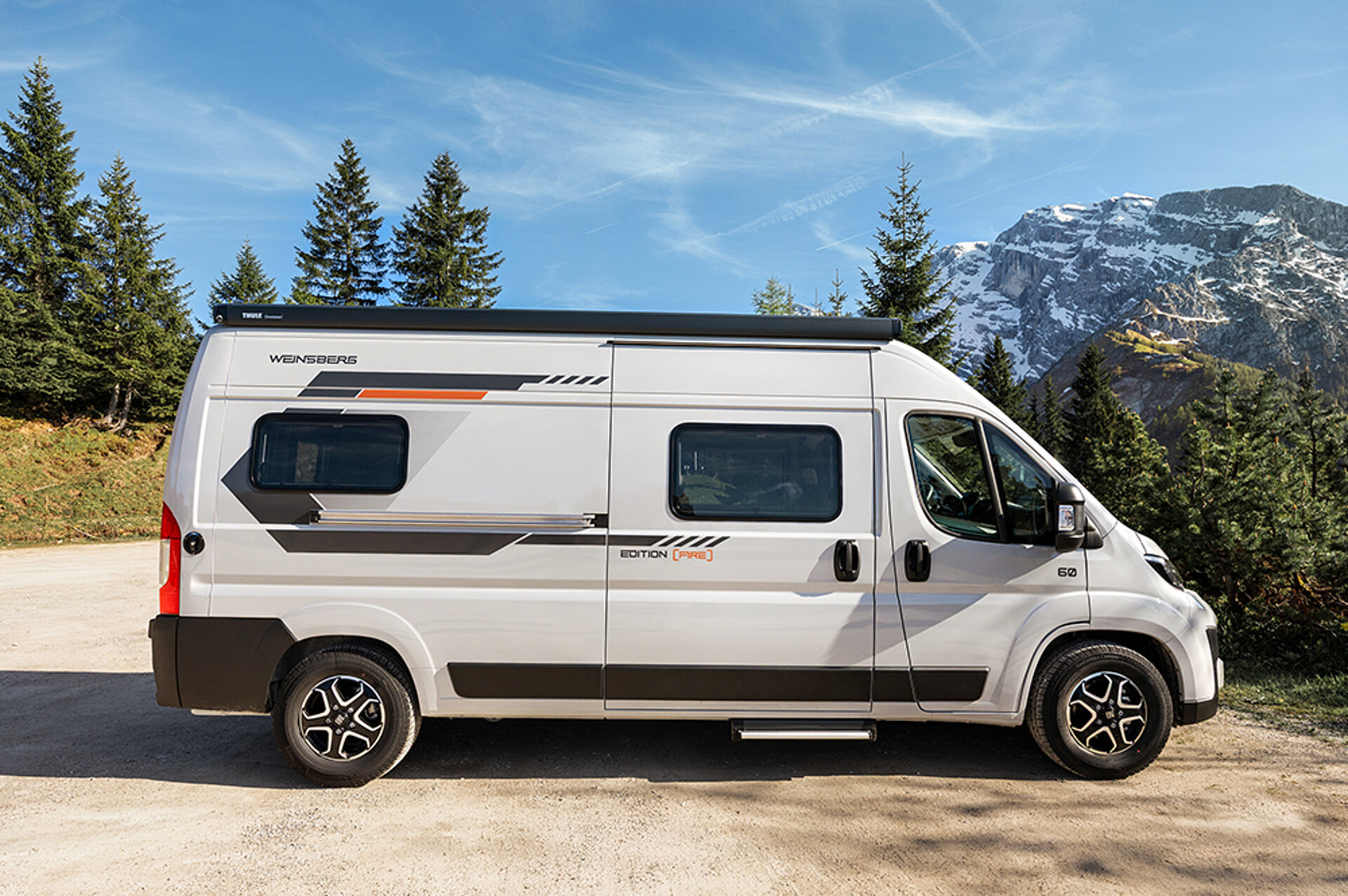 Weißer Camper Van in einer Berglandschaft.