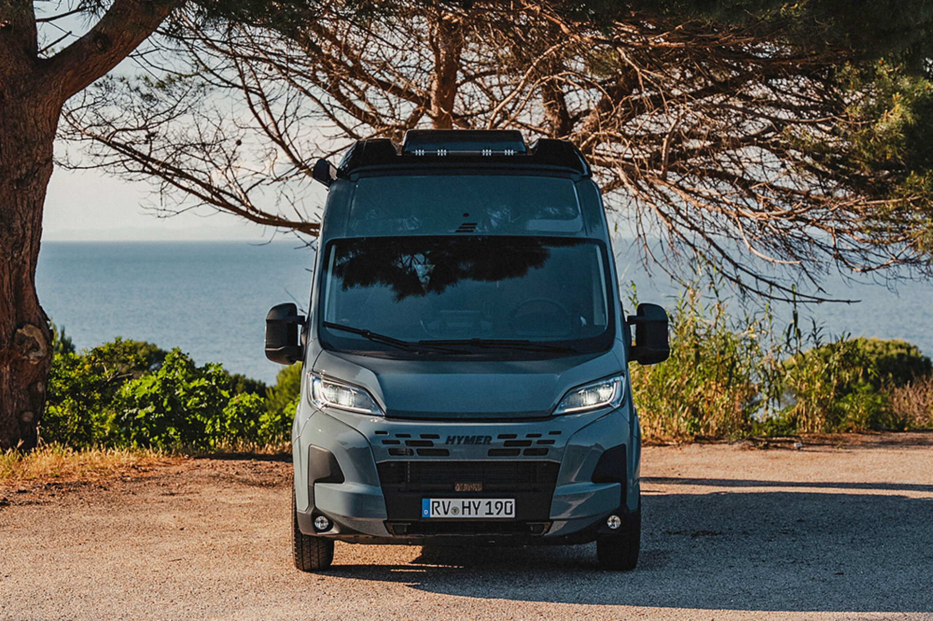 Frontale Ansicht auf den HYMER Redwood, der vor einem Baum steht.