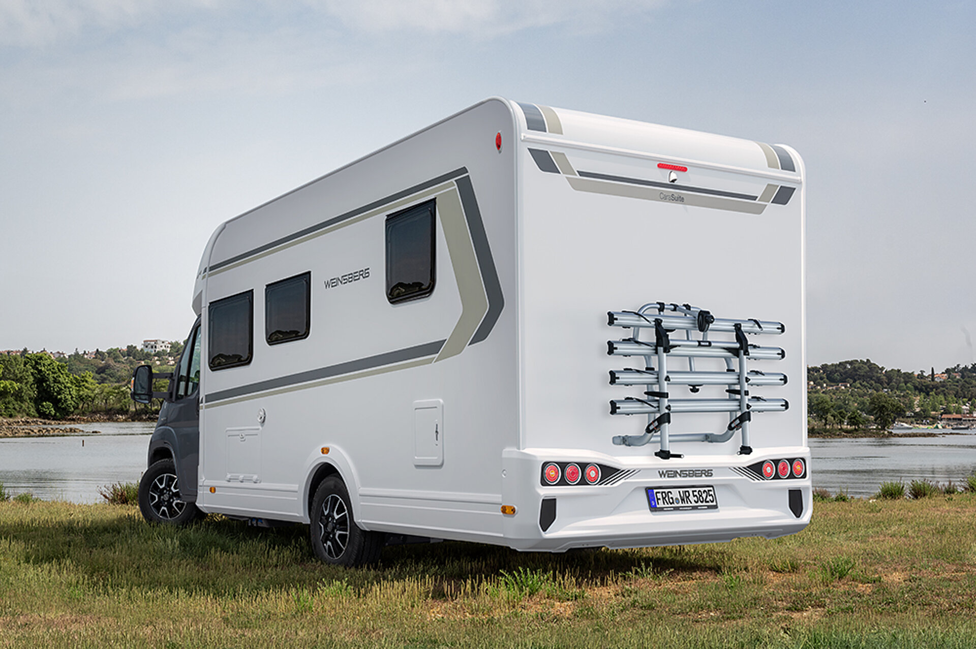 Weißes Reisemobil von hinten auf einer Wiese.