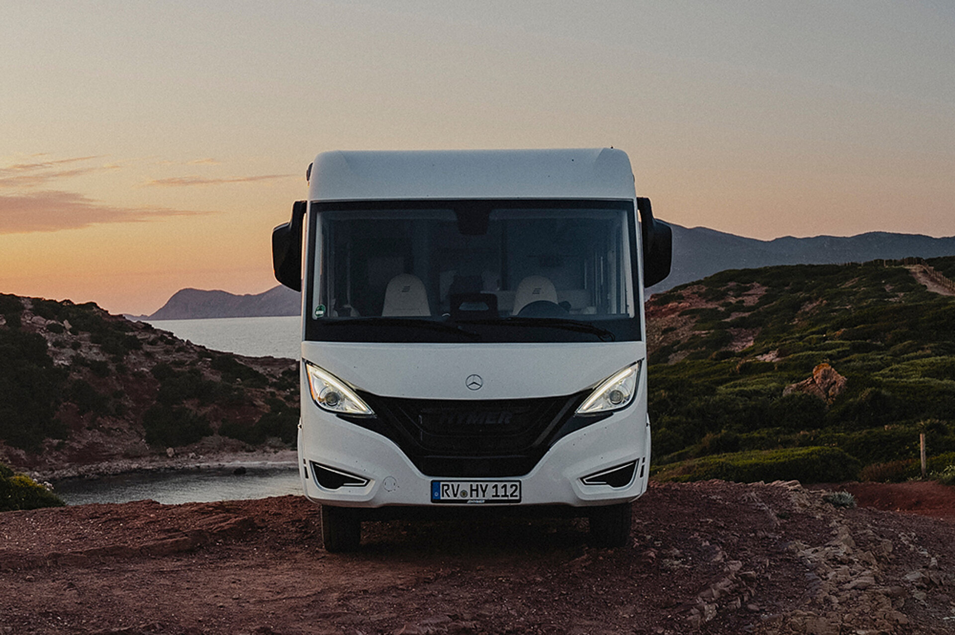 Ein integrierter HYMER B-Klasse ModernComfort steht vor einer Küste im Sonnenuntergang.