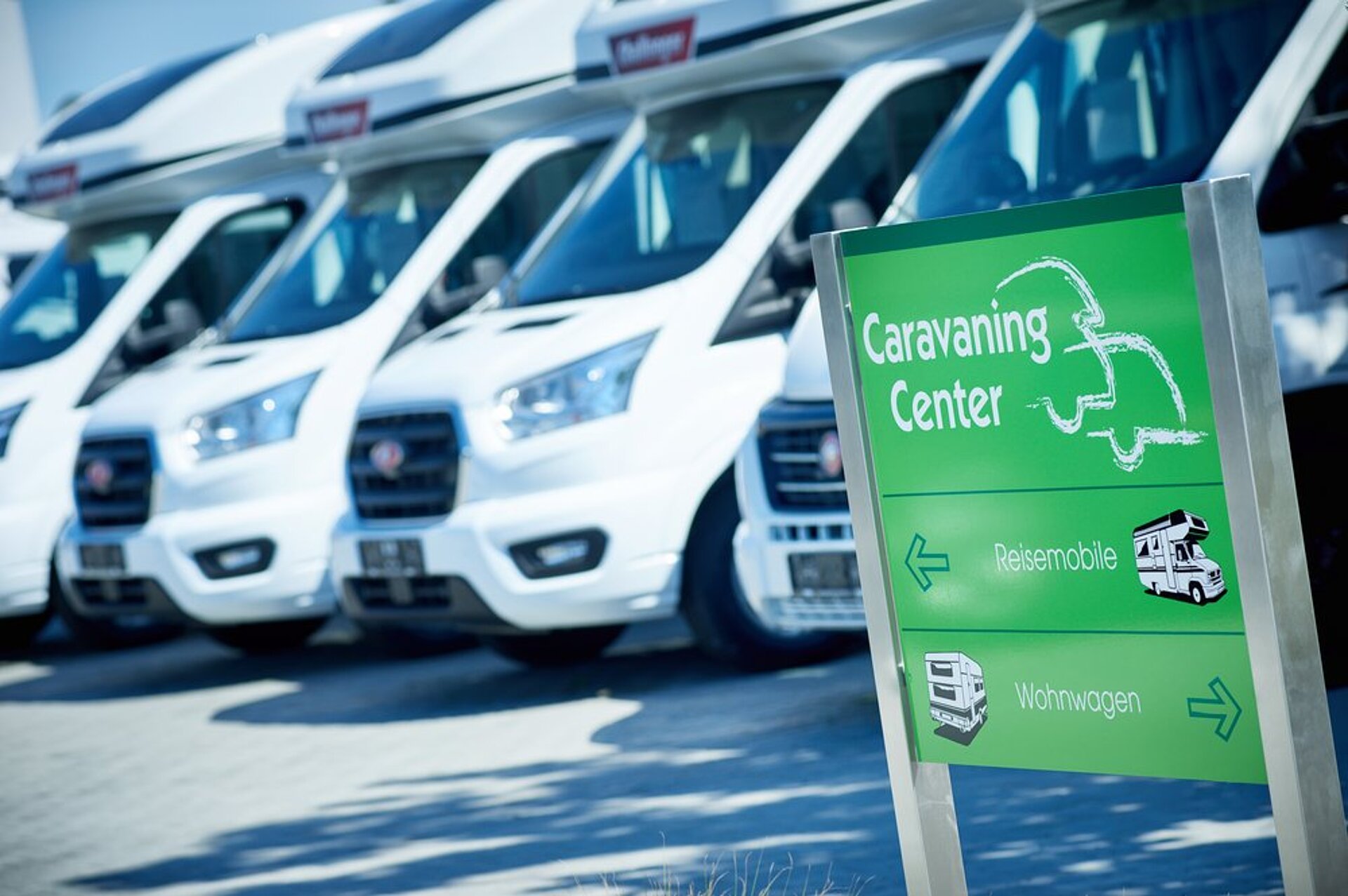 Mehrere Fahrzeuge nebeneinander mit Firmenschild im Vordergrund.