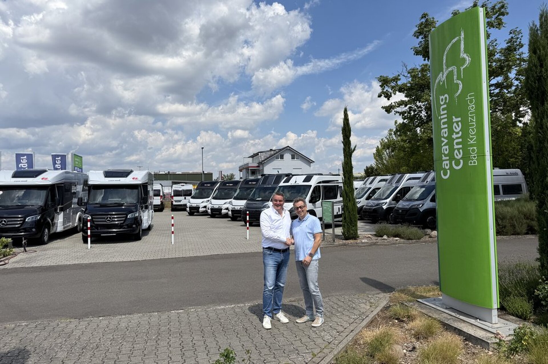 Zwei Menschen stehen auf dem Firmengelände vom Caravaning Center Bad Kreuznach und geben sich die Hand.