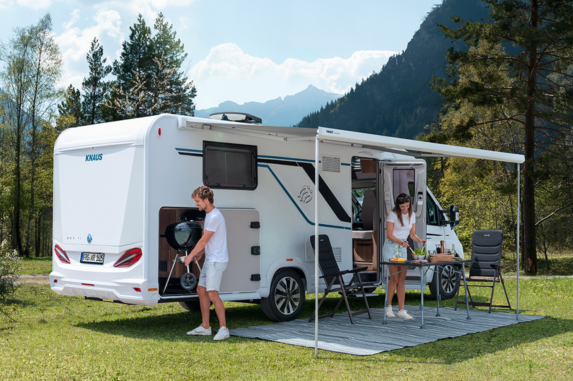 A couple prepares dinner in front of the KNAUS SKY TI.