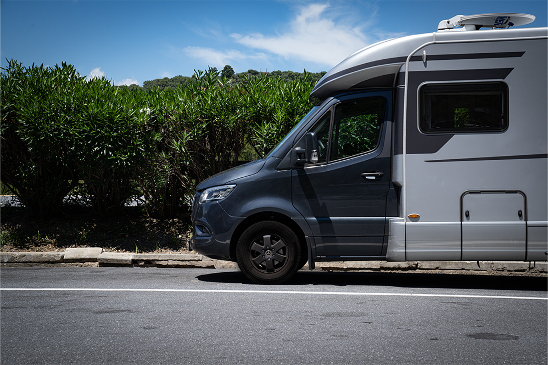 Een witte camper op een weg in een groen landschap.