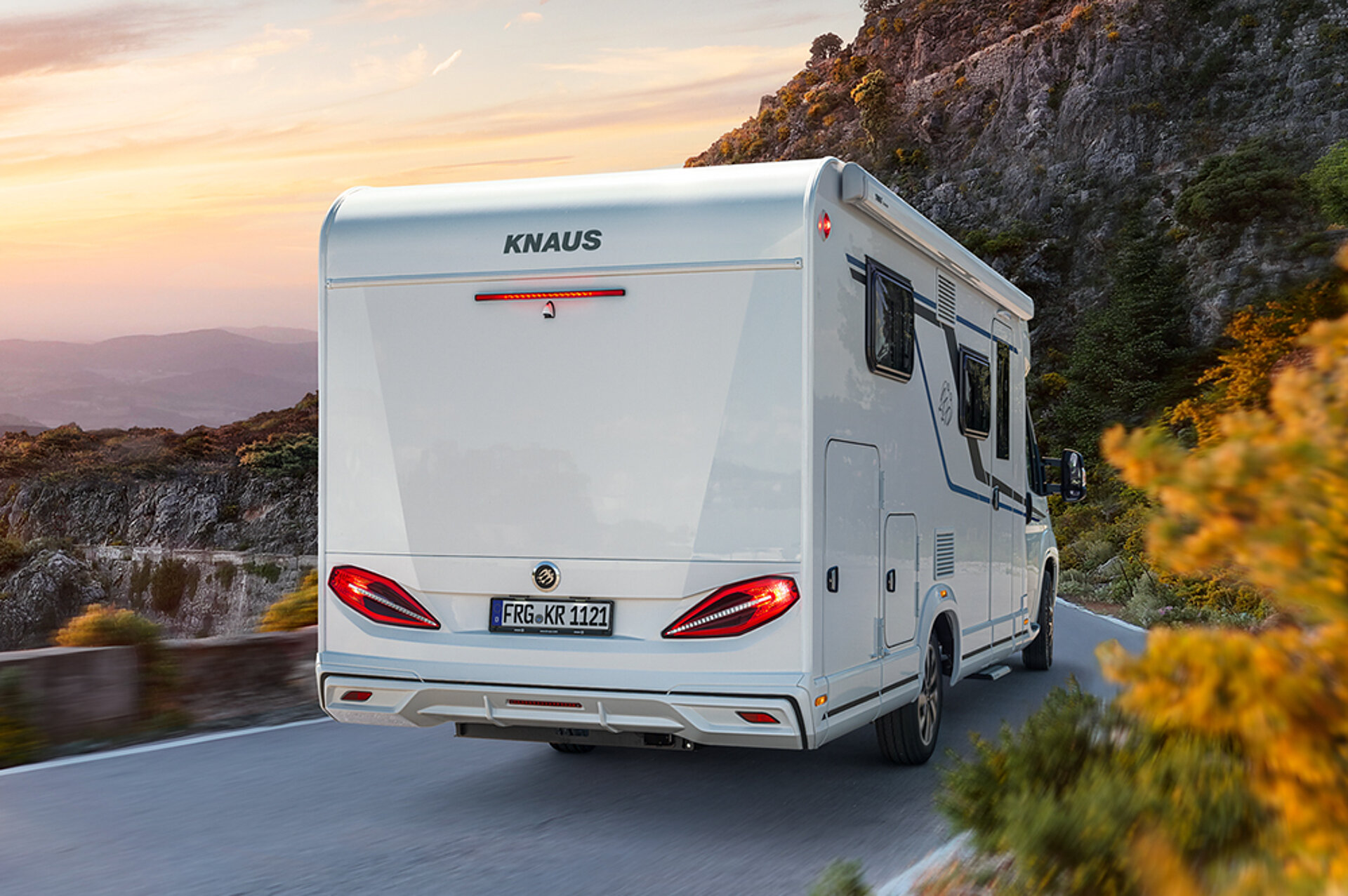 A KNAUS VAN TI drives down a road into the sunset.