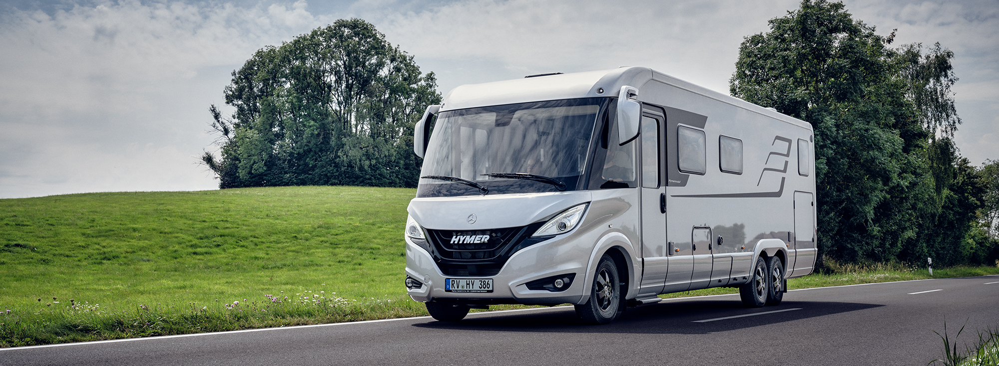 Een witte camper op een weg in een groen landschap.