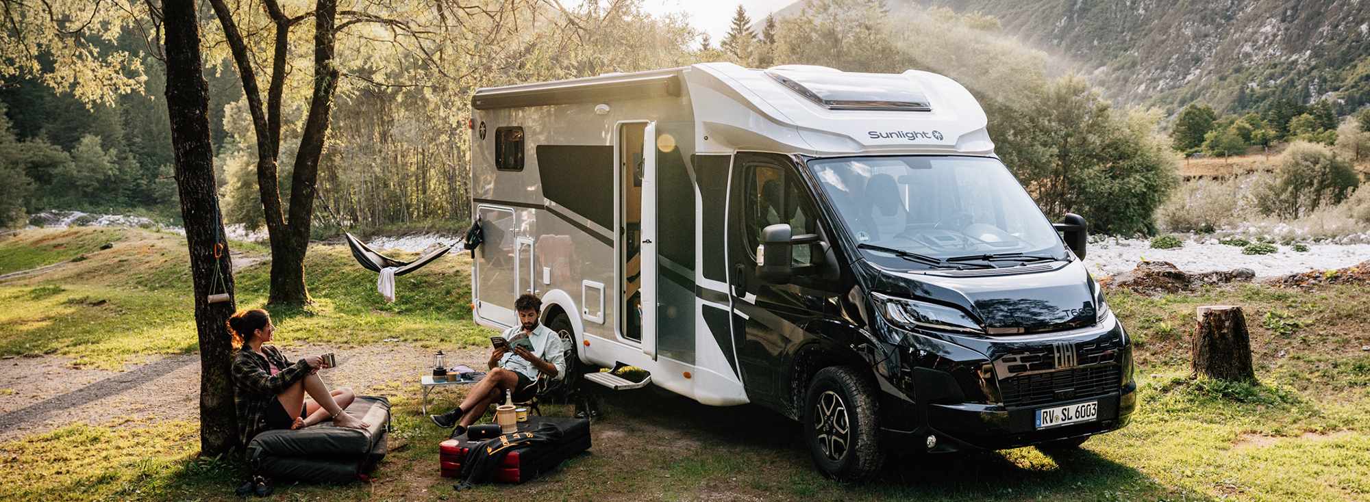 Sunlight Reisemobil in einer Landschaft mit Personen im Vordergrund.