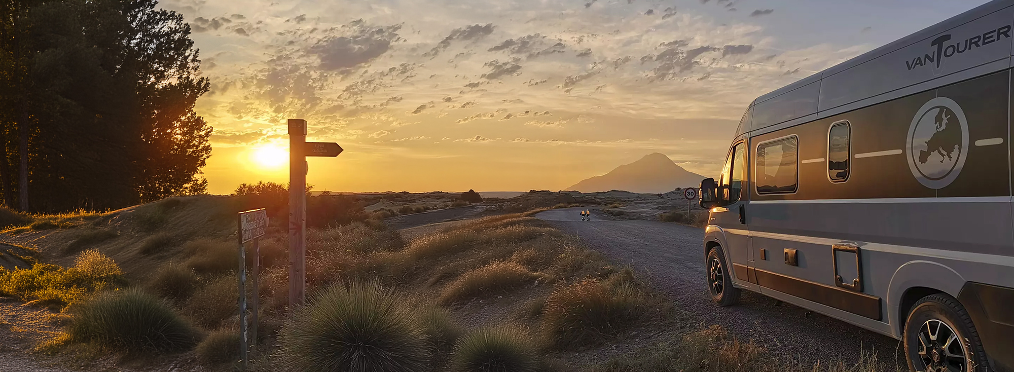 Ein heller Camper Van in einer Wüstenlandschaft.