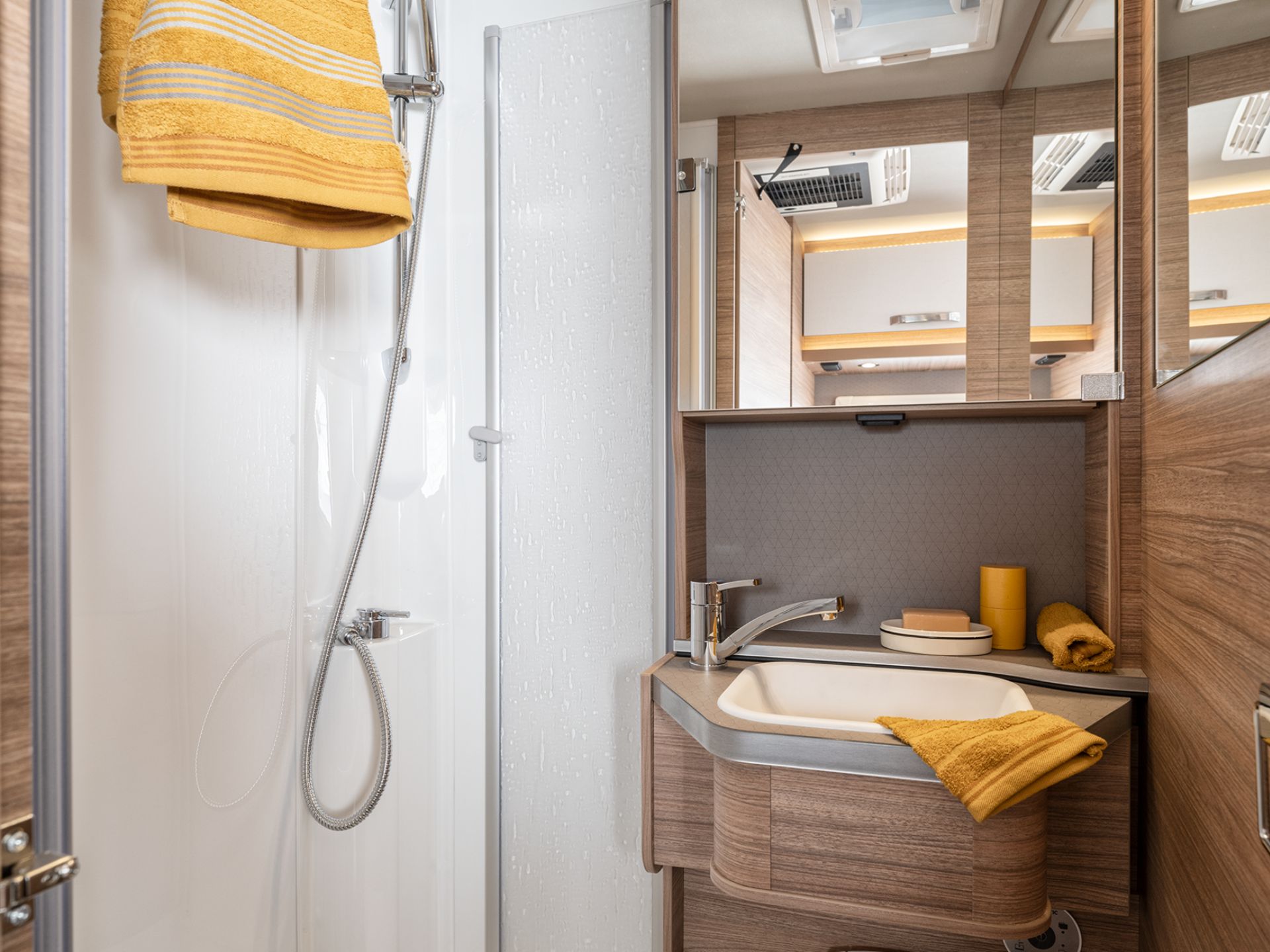 Badezimmer in einem Wohnmobil mit Handtüchern über der Duschtür und am Waschbecken.