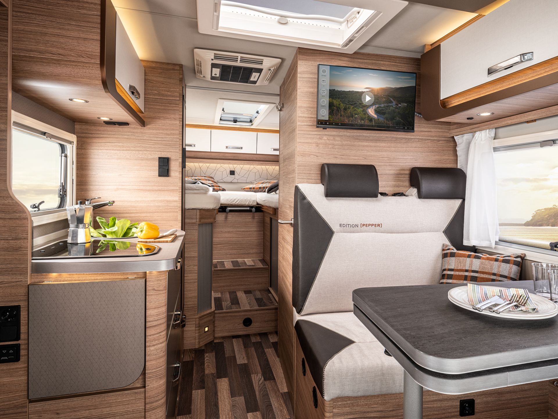 Blick in den Innenraum eines Wohnmobils mit Sitzgruppe, Küche und Schlafplatz