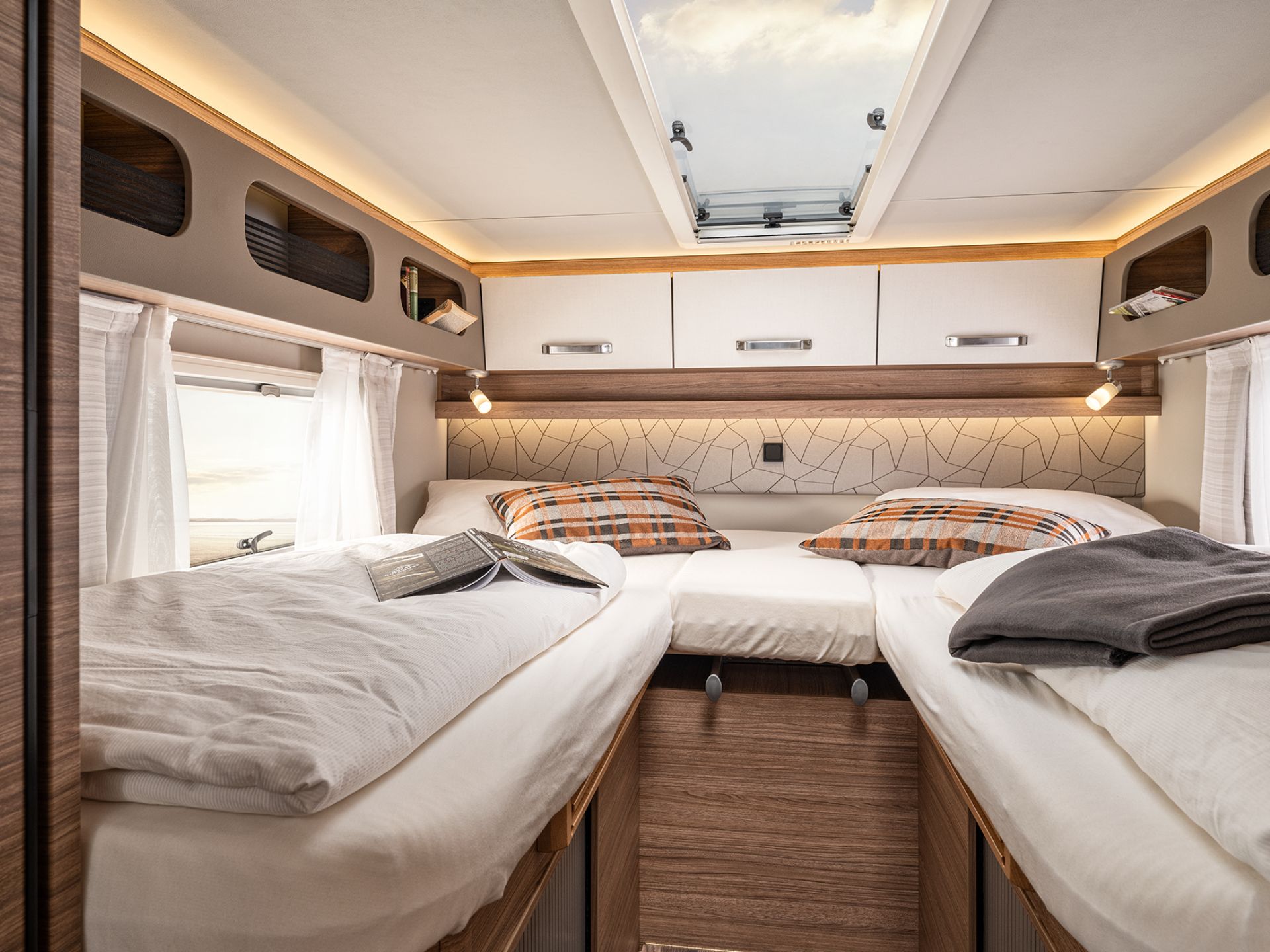 Der Schlafbereich mit getrennten Betten in einem Wohnmobil mit Bettwäsche und Dekokissen