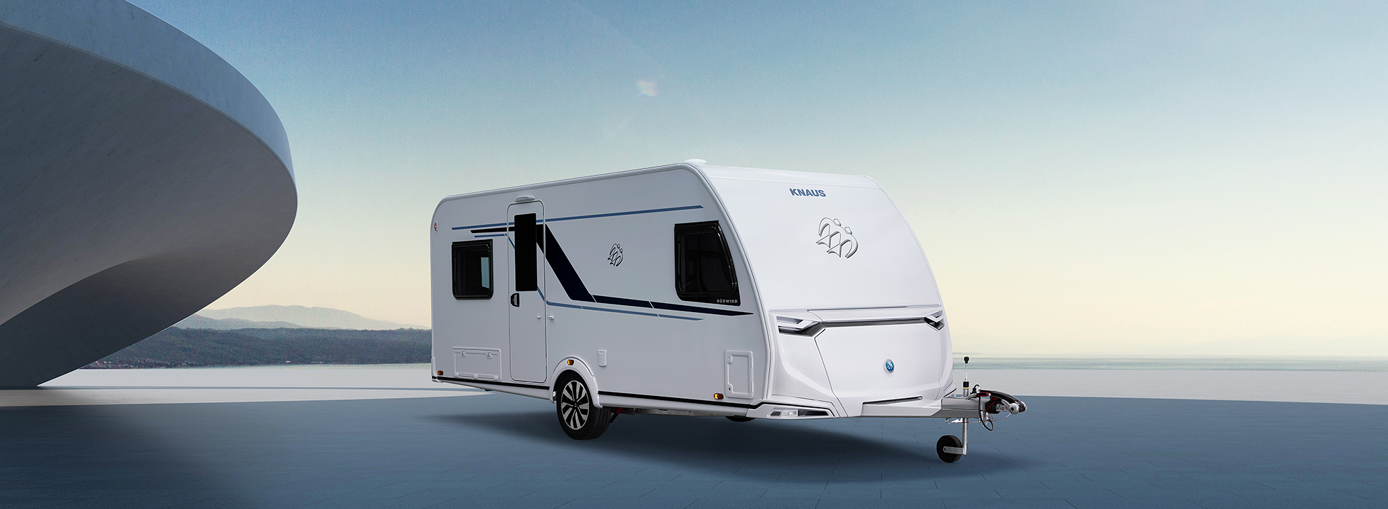 Een witte caravan staat voor een futuristische achtergrond.