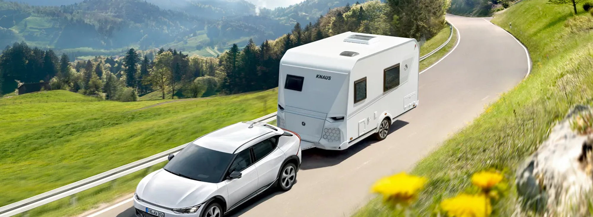 Une caravane blanche est tractée par une voiture blanche.