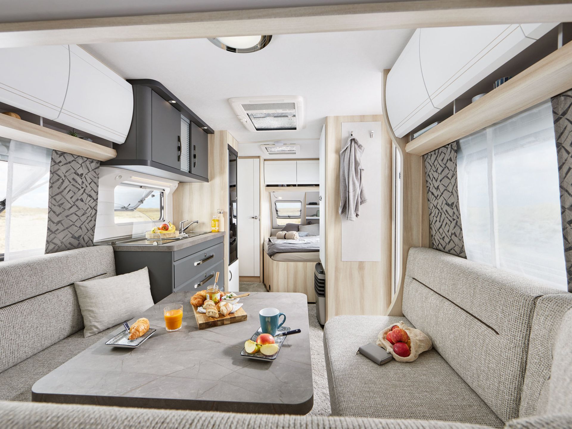 Innenraum Wohnwagen Blick auf einen gedeckten Tisch zur Küche und Bett